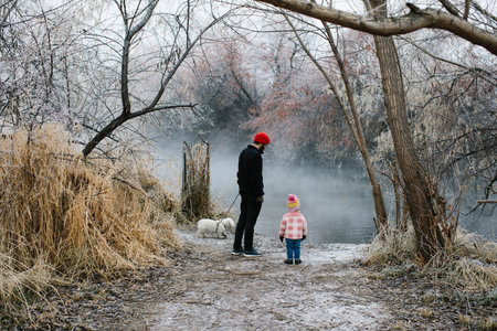 Toddler girl with her father looking out at a foggy winter lakeの写真素材