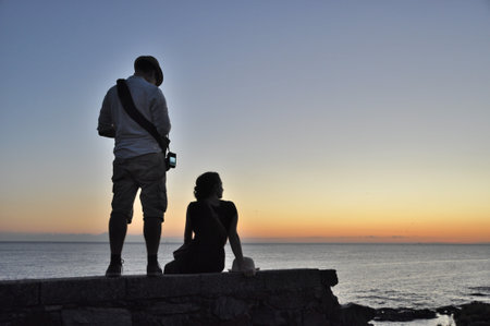 tourist couple enjoying the sunset on the coastの写真素材