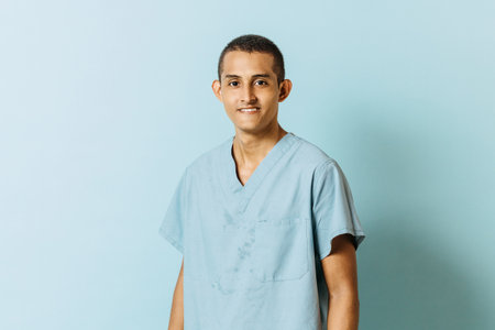 portrait of a smiling young latinx man in health uniform looking at camera. college education concept.の写真素材