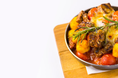 Stew with vegetables in a pan on a cutting board, white backgroundの写真素材