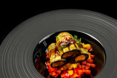 Grilled eggplant rolls with red lentils on a black plate and black backgroundの写真素材