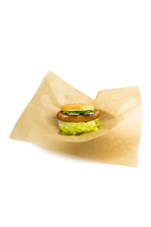 Sausage in a roll with lettuce on paper, white backgroundの写真素材