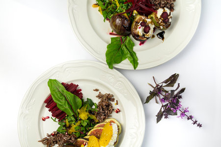 Fig salad with goat cheese and beets, on a white plate and white background, two platesの写真素材