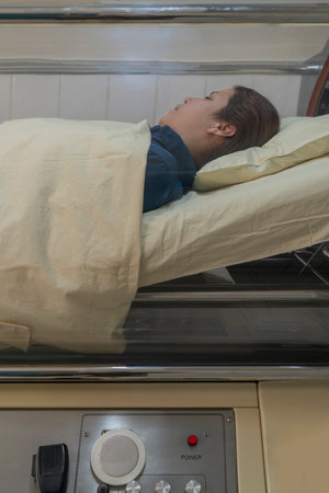 Vertical photo of a woman inside a hyperbaric treatment machine in a clinic