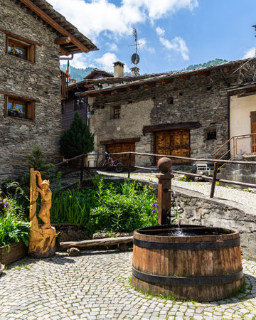 A fountain among typical alpine houses in Pontechianale, Varaita Valley, Piedmont, Italyの写真素材