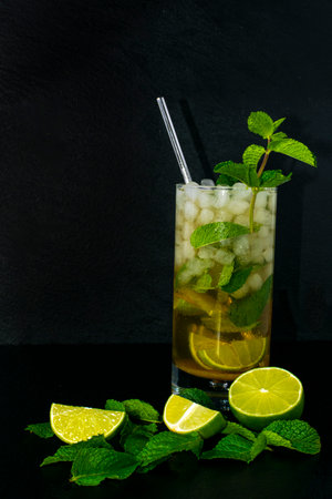 Mojito cocktail with fresh mint, lime and ice cubes with black slate background.の写真素材