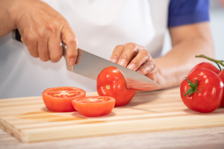 female hands cutting tomato on a wooden cutting board: Selective focus. Diet and healthy food conceptの写真素材