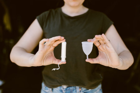 woman holding a tampon and a silicone menstrual cupの写真素材