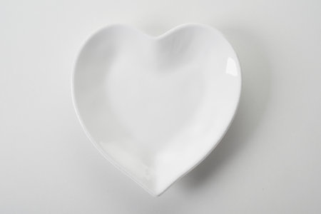Top view of empty clean heart shaped white ceramic serving plate on white backgroundの写真素材