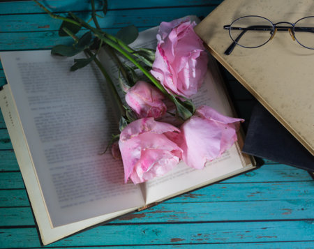 a bouquet of pink roses and books on rustic woodの写真素材