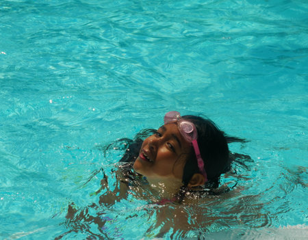 Beautiful photo of a little girl bathing in a poolの写真素材