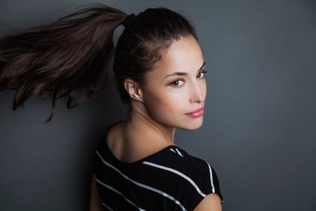 young pretty woman portrait with ponytail in motion studio shotの写真素材
