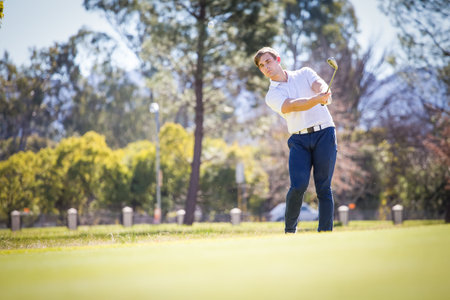 Close up view of a golfer playing a chip shot on a golf course in south africa with back light.の写真素材