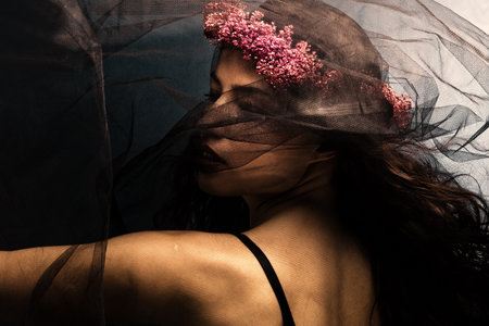 woman in dancing motion  under black veil with wreath of flowers in hairの写真素材