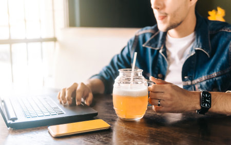 person working on a laptop while drinking a beer. digital nomad concept