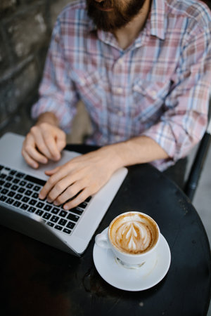 Young man  working on his laptop at an outdoor coffee shopの写真素材