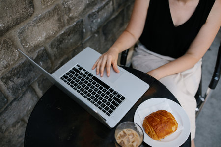 Young professional woman working remotely from an outdoor coffee shopの写真素材