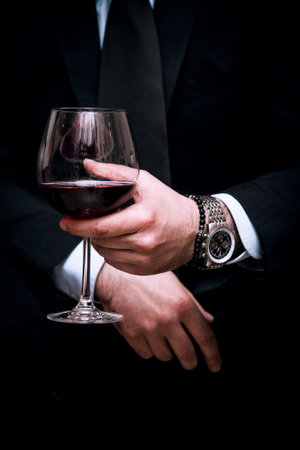 adult elegant man hold glass of red wine, close up, indoor shot, selective focusの写真素材