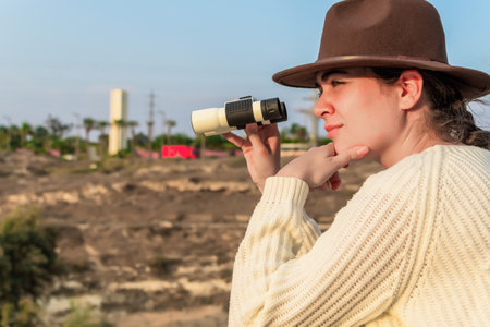 Side view of young caucasian woman with hiking hat, traveler, tourist, with binoculars.の写真素材