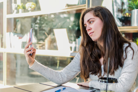 Young woman talking in video chat with her friend via smart phone.