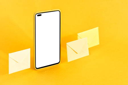 Smart phone and envelopes on yellow background. Online communication concept.