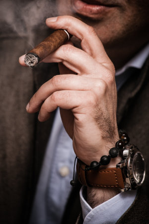 elegant man wearing suit and white shirt smoking  cigar indoor shot, closeup, selective focusの写真素材