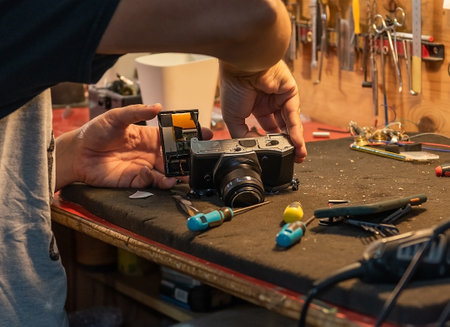 Close-up of a Caucasian male technician's hands repairing a camera at the service center.