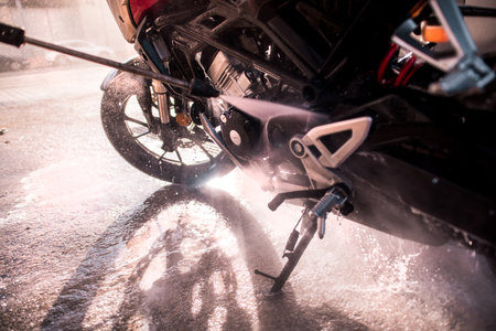 Detail of a pressurized water gun cleaning areas of the motorcycle