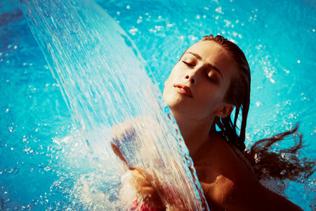 young woman refresh in pool under waterfall, retro colorsの写真素材