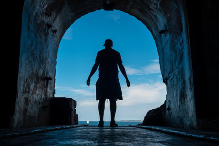 A young man in the tunnel to the sea at the Fort des Capucins a rocky islet located in the Atlantic Ocean, Roscanvel, on the Crozon peninsula in France.の写真素材