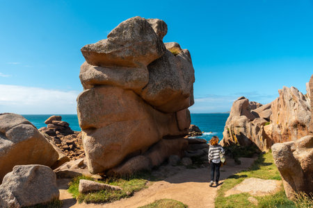 A young woman on a footpath on the coast next to Lighthouse Mean Ruz, port of Ploumanach, in the town of Perros-Guirec, Cotes-d'Armor, in French Brittany, France.の写真素材