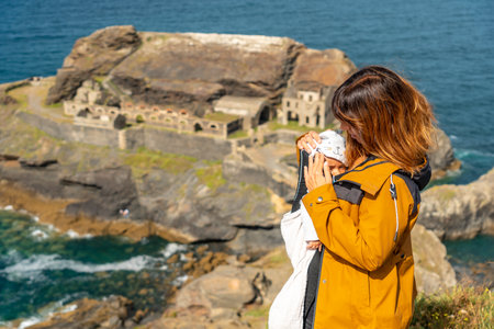 A young mother with her baby looking at the Fort des Capucins a rocky, clifftop islet in the town of...