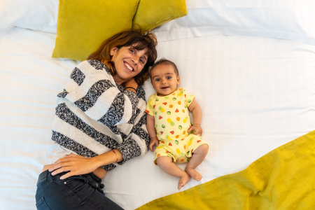 Young mother with her baby on the bed in her bedroom, lifestyle portrait of a young mother, family...