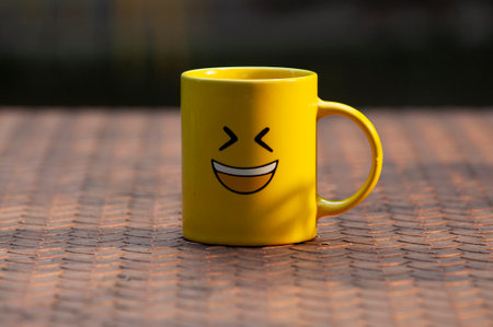 Yellow glass with smiling emoticon on metal table, Conceptualの写真素材