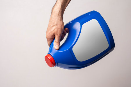 A male hand holging a blue kitchen detergent bottle with closed cap, lable selection path included.の写真素材
