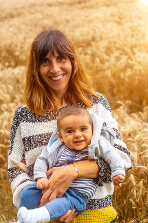 A young smiling mother with her baby in a yellow straw field in French Brittany in the summer of July, near the Broceliande forest. Franceの写真素材