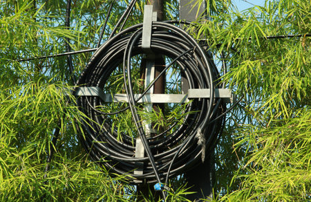 Fiber optic cable reel hanging on iron pole with bamboo leaves in the background