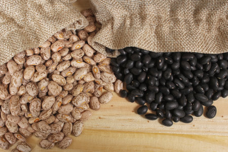 Pinto Beans and Black Beans in Burlap Bag on Wooden Backgroundの写真素材