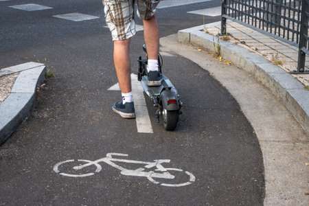 Detail of an electric scooter driven by a man while waiting his turn to cross a road. E-Scooter is allowed in bike lanes.の写真素材