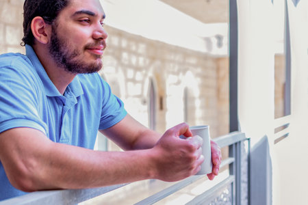 Side view of a happy man contemplating views with coffee cup on a balcony.の写真素材