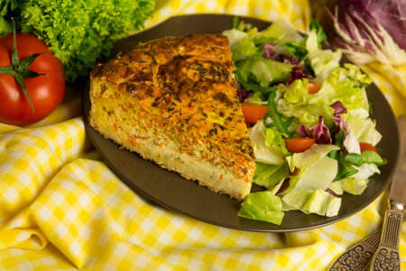 Carrot tart with salad on a yellow background, close up