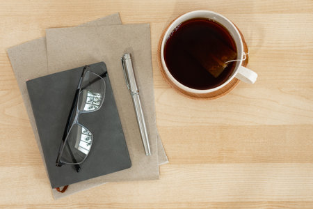 Notebook, recycled paper, pen and tea cup on business desktop.の写真素材