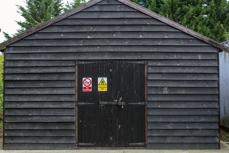 Flammable and no smoking sign on the doors on a large wooden shed.