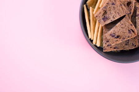 brown bread slices in a porcelain bowl on a pink surface