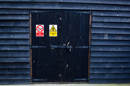 Flammable and no smoking sign on the doors on a large wooden shed.の写真素材