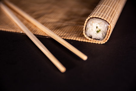 Closeup of chef hands preparing japanese food. Japanese chef making sushi at restaurant. Young chef serving traditional japanese sushi served on a black stone plate.の写真素材