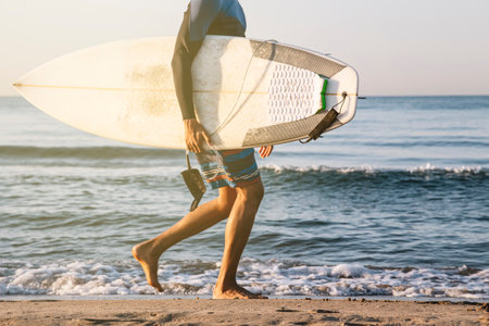 Unrecognizable surfer running along the shore of the beach with surfboardsの写真素材