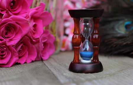 Vintage Hourglass With Pink Roses and Peacock Feathersの写真素材