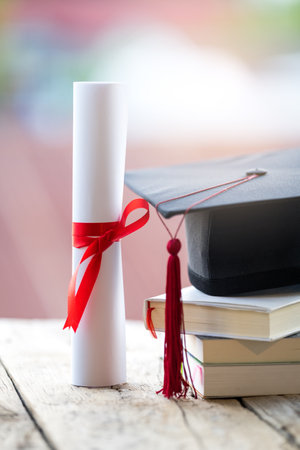 Close-up selective focus of a graduation cap or mortarboard and diploma degree certificate put on tableの写真素材