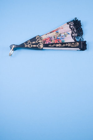 view of a beautiful decorated floral hand fan on a blue surfaceの写真素材